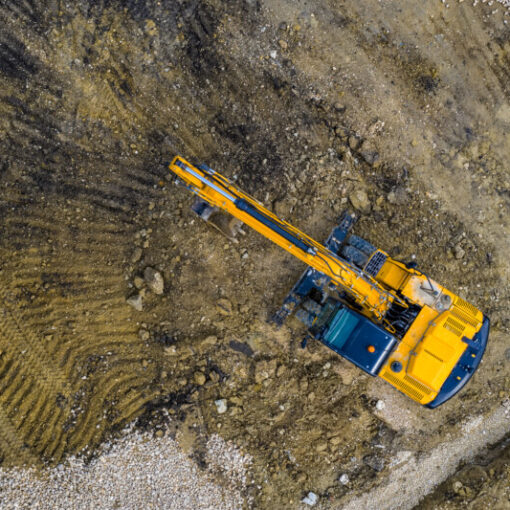 Stunning aerial view of the stopped yellow excavator at a construction site
